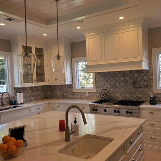 Bright, modern kitchen with white cabinetry and marble countertops.