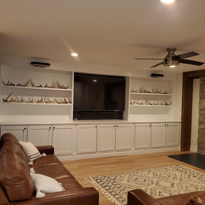 Cozy living room with a large TV, built-in shelves, and a brown leather sofa.
