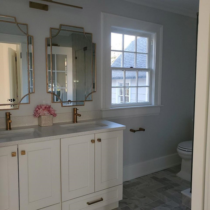 Bright bathroom with white cabinetry and a window letting in natural light.